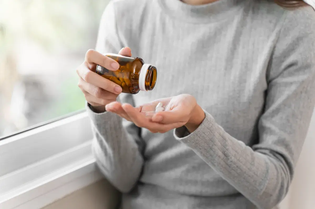 Patient taking out pills beside window